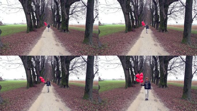 女孩带着红色心形气球在公园里散步