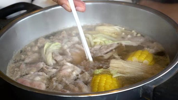 4k镜头用筷子、sha锅和Sukiyaki搅拌的煮汤火锅中蘸肉片的场景日式美食概念