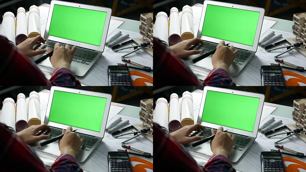 设计师使用带绿屏的笔记本电脑，