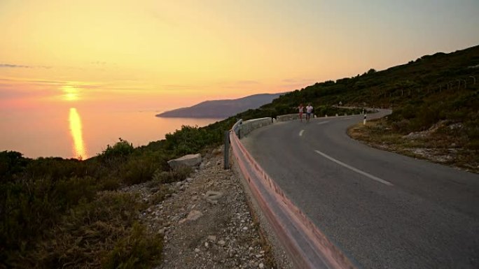 快乐的情侣在日落时在沿海公路上跳跃