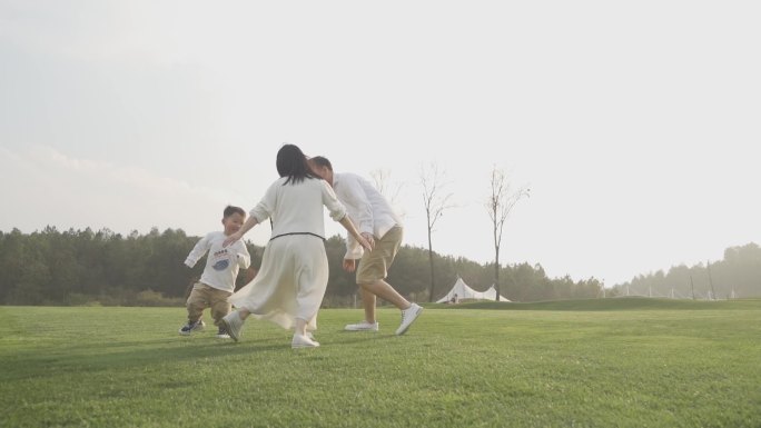 爸爸妈妈陪孩子玩游戏草地奔跑温馨一家三口