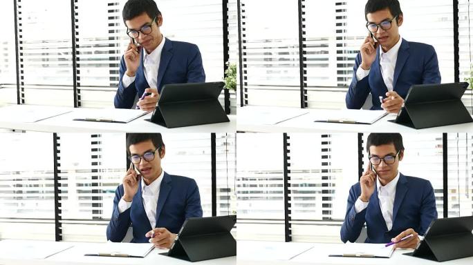 商人在办公室用数字平板电脑在办公桌前接听手机