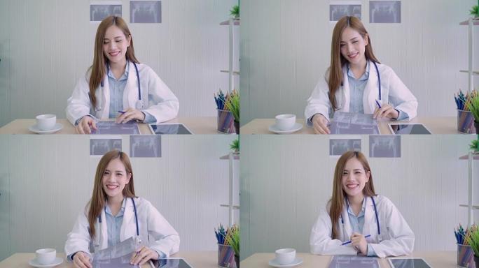 自信的亚洲女医生坐在办公桌前，在医疗办公室对着镜头微笑，保健和预防理念。