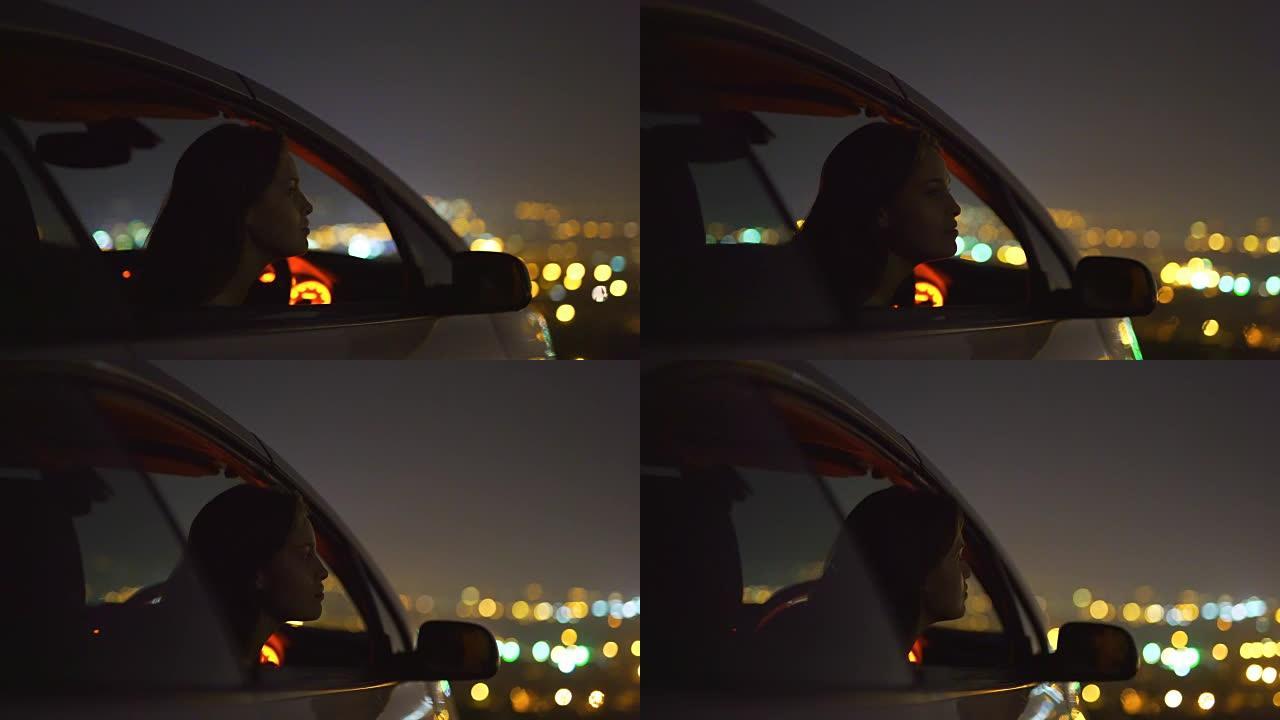 那个女人坐在城市灯光背景下的汽车里。晚上时间