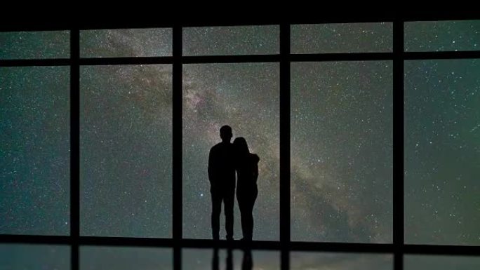 站在星空背景的窗户附近的男人和女人。时间流逝