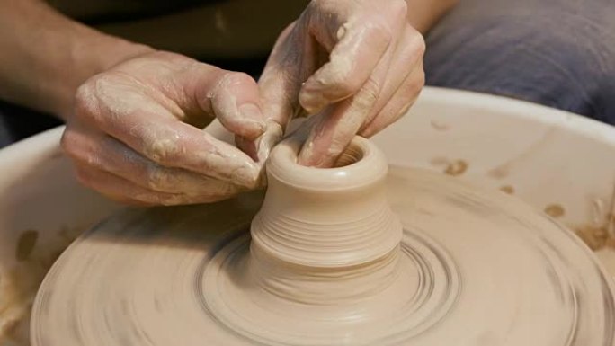 人的手在陶工的轮子上制作粘土器皿