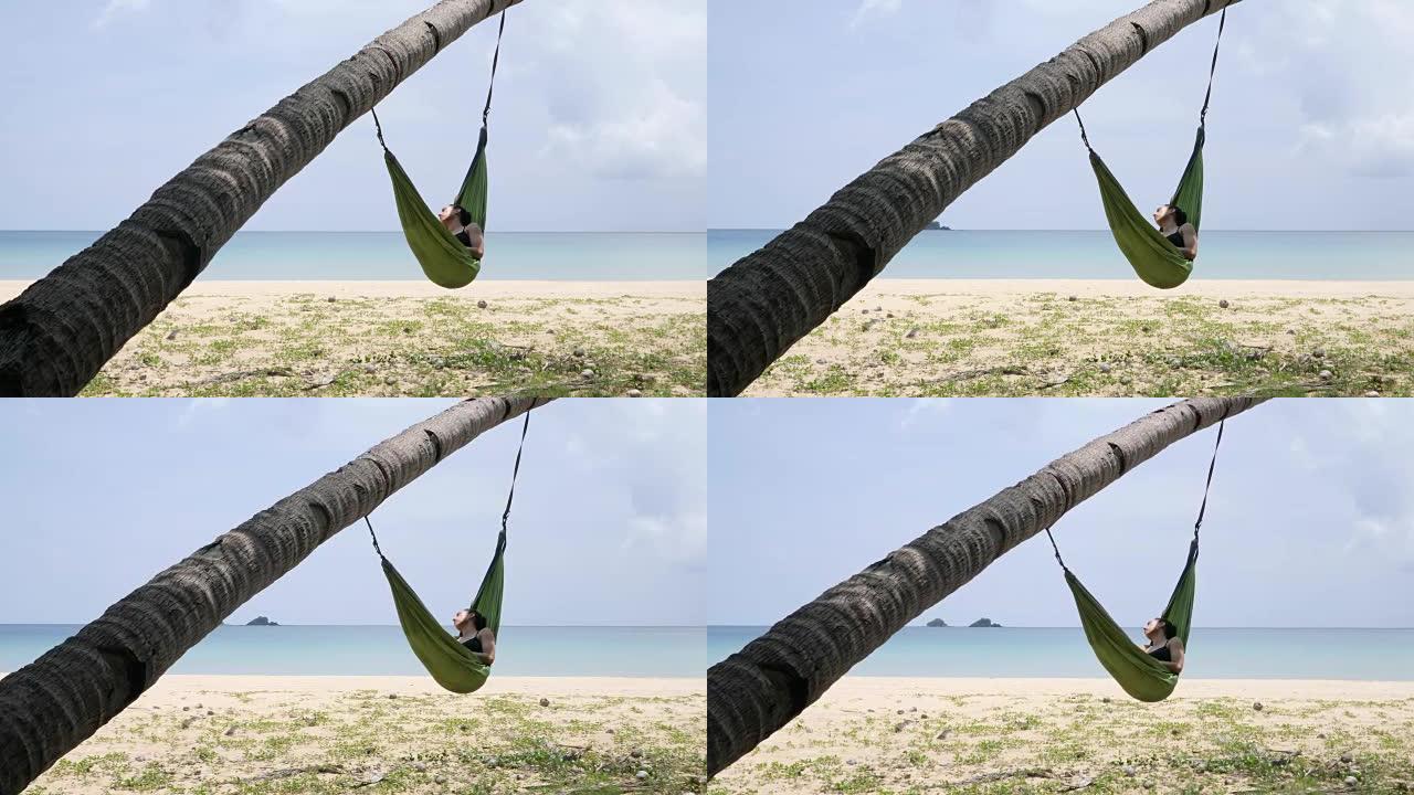 女人睡在悬挂在棕榈树上的吊床上