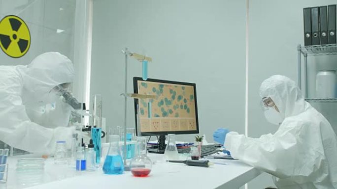 医学研究科学家在安全的高级研究实验室工作，在计算机上工作，在显微镜下观察物质。实验室明亮而现代