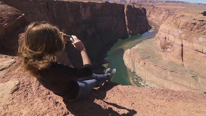 年轻女游客用智能手机拍摄大峡谷
