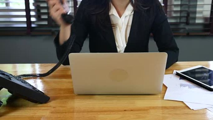 女商人用笔记本电脑在办公桌前接电话