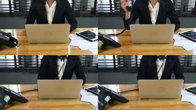 女商人用笔记本电脑在办公桌前接电话