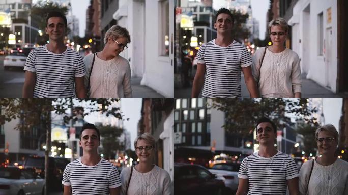 快乐微笑的浪漫情侣在纽约Soho晚间散步时牵着手交谈，享受夜城