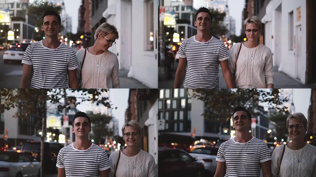 快乐微笑的浪漫情侣在纽约Soho晚间散步时牵着手交谈，享受夜城
