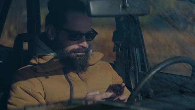 微笑的男人在车里用手机发短信。