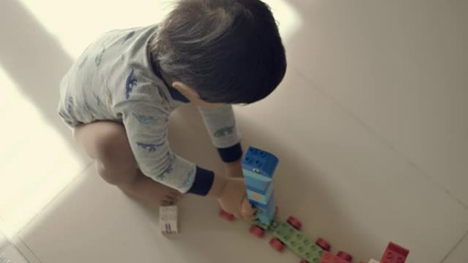 快乐的男婴玩积木光脚男孩小火车模型独自一