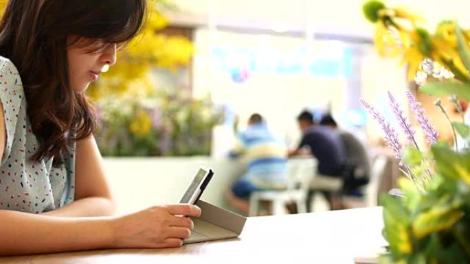 4K: 年轻女子在咖啡店使用数字平板电脑