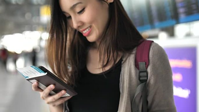 亚洲年轻女子在机场使用带护照的智能手机旅行