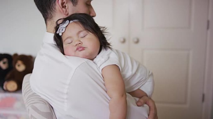 揭示了一个婴儿在父亲的怀抱中睡觉