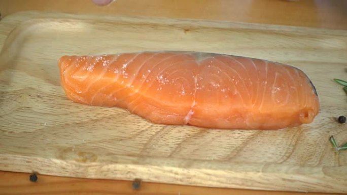 慢动作-美食厨师或烹饪用海盐和辣椒粉调味新鲜的熟食店鲑鱼鱼。