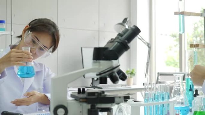 亚洲女性医学研究科学家在实验室中通过显微镜观察