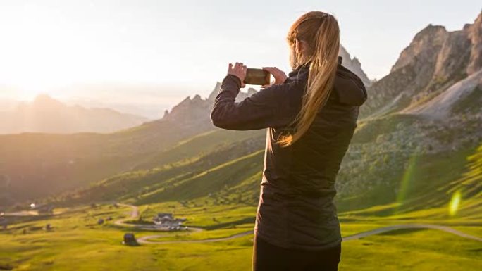 女人在山腰拍摄日落的照片