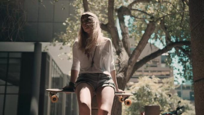 坐在街上玩滑板的女人