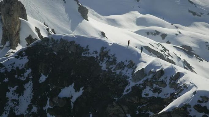 登山者在白雪覆盖的山顶上行走