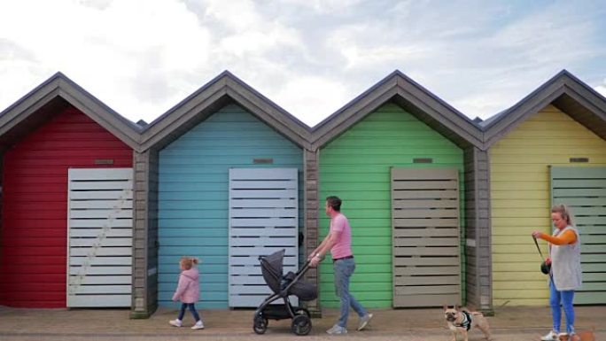 一家人走过色彩丰富的海滩小屋