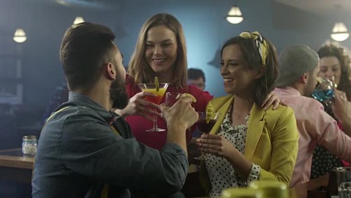男人和两个女人在鸡尾酒吧喝酒聊天