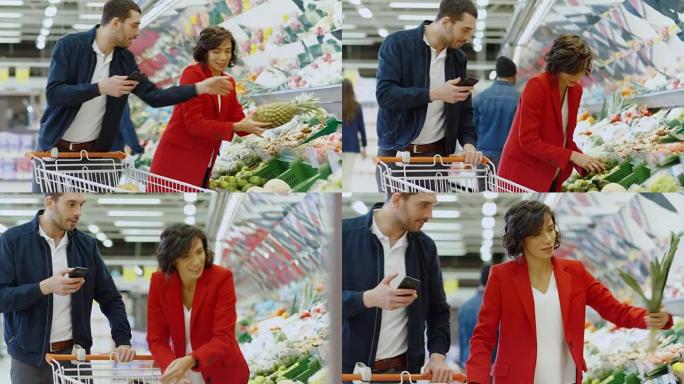 在超市: 幸福的夫妇购物，在新鲜农产品区选择水果和蔬菜。男人在智能手机上指向清单并推动购物车，女人选