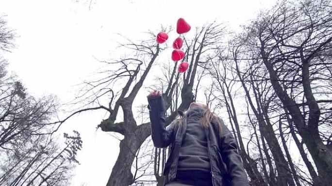 女孩在公园里放飞红色心形气球