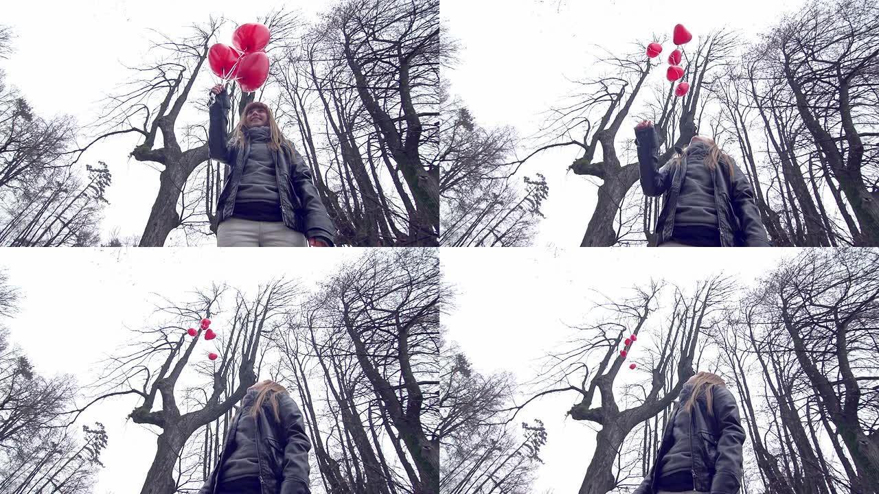 女孩在公园里放飞红色心形气球