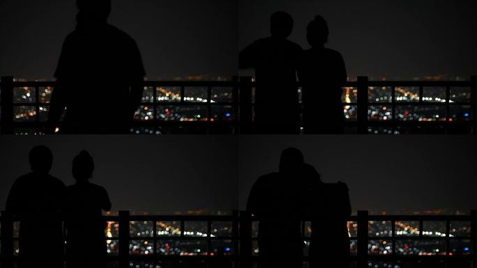 年轻夫妇在夜间城市场景中观看城市背景上的星星，4k(UHD)