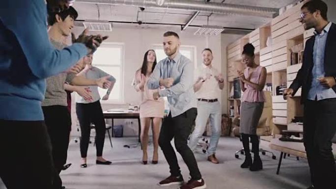 年轻的欧洲商人在办公室聚会上与同事围成一圈跳舞，庆祝职业晋升慢动作