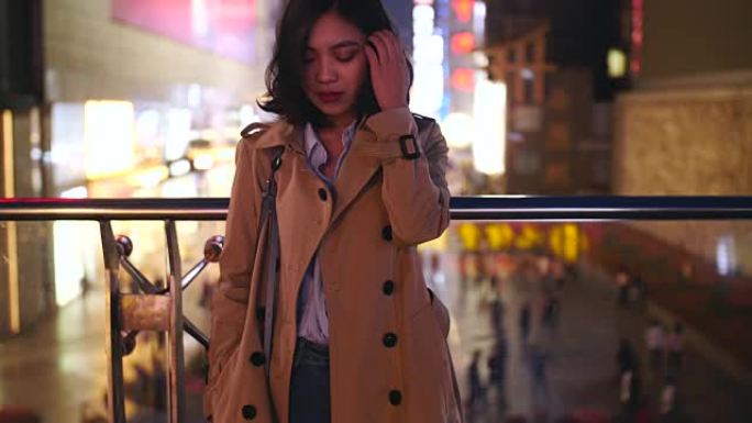 一个年轻年轻的亚洲女人的慢动作晚上在城市里抚摸她的头发