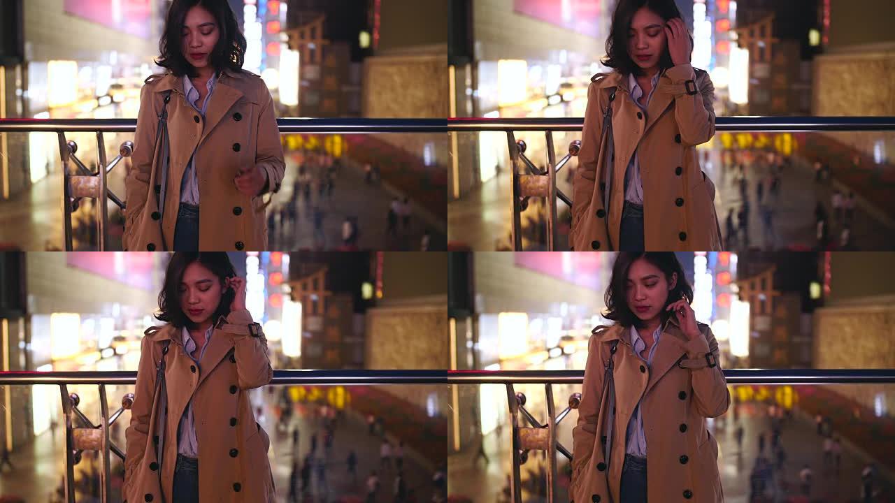 一个年轻年轻的亚洲女人的慢动作晚上在城市里抚摸她的头发