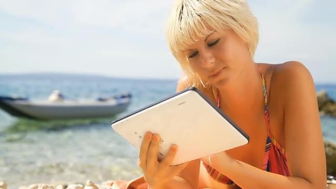 高清：性感女人在海滩上使用数字平板电脑