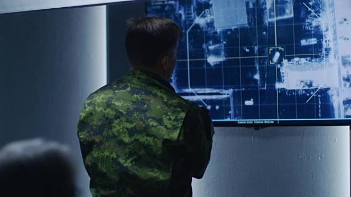 军人/军官在墙上电视屏幕上观看目标的卫星监控录像/汽车跟踪。在监控中心/系统控制室的秘密军事间谍行动