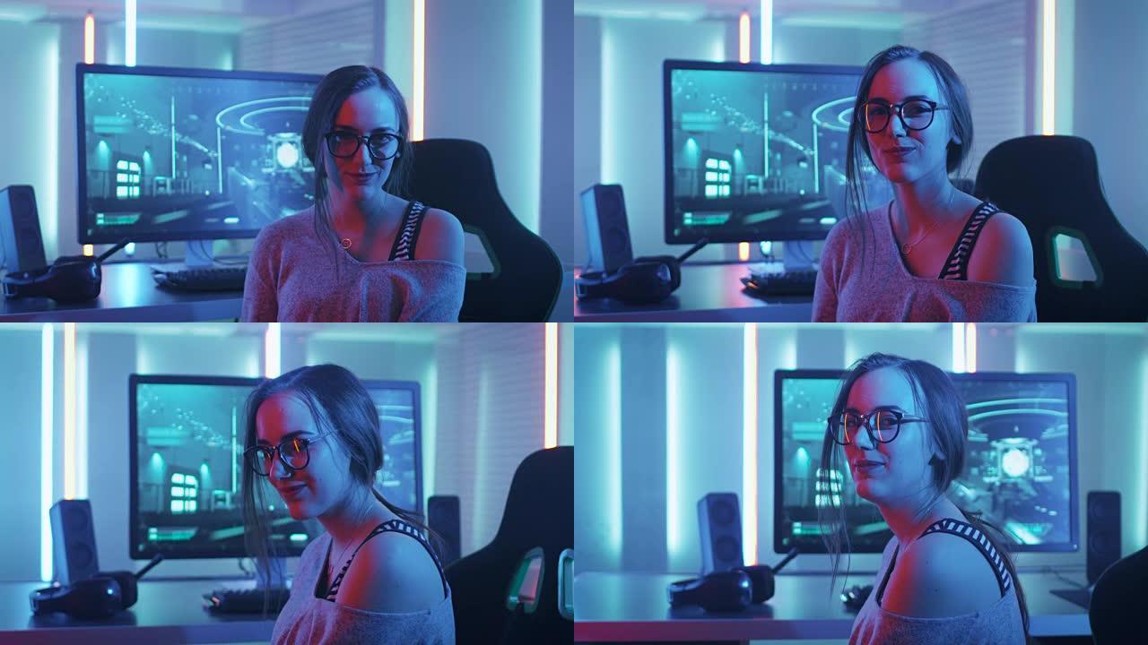 美丽的年轻职业玩家女孩坐在她的个人电脑和赢得在线视频游戏锦标赛的肖像看着相机。迷人的极客女玩家戴着眼