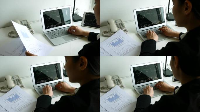 女商人在文件纸和笔记本电脑屏幕上查看财务图表，4K(UHD)