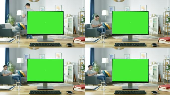 现代个人电脑，绿色模拟屏幕显示，站在舒适的客厅的桌子上。一个拿着手机的男人在椅子上放松。