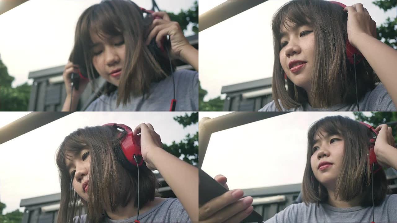 美丽的年轻亚洲妇女在城市的智能手机上听音乐。年轻的亚洲女人在街上放松听音乐。