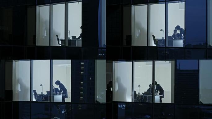 摩天大楼外的航拍画面: 商人和女商人站在办公室的窗户里聊天。晚上检索商业区的飞行镜头和在大城市工作的