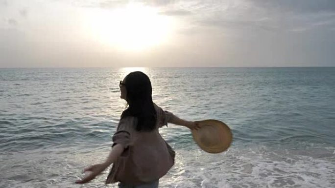 亚洲年轻女子在日落时奔向海滩