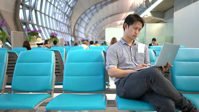 亚洲男子在机场使用笔记本电脑