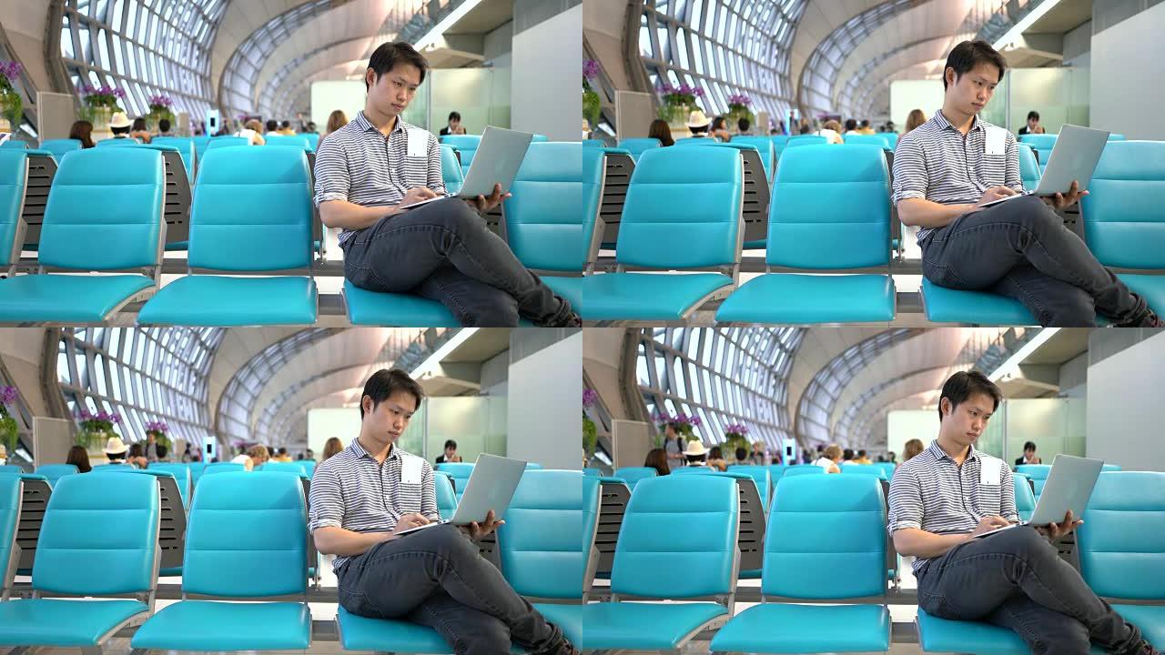 亚洲男子在机场使用笔记本电脑