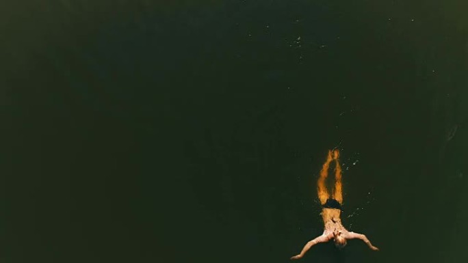 女人在湖里游泳。夏季活动