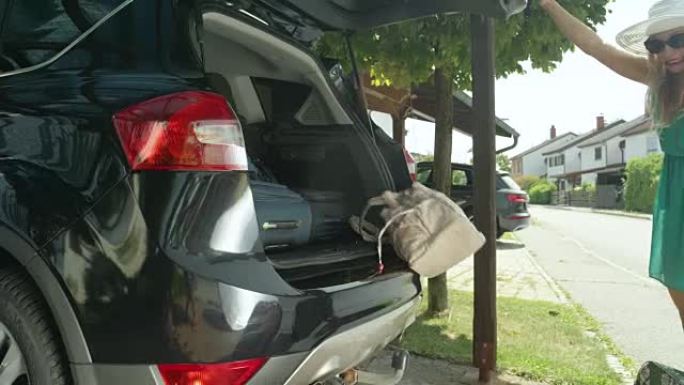 慢动作: 快乐的女人打开黑色SUV的后备箱，行李掉了出来。