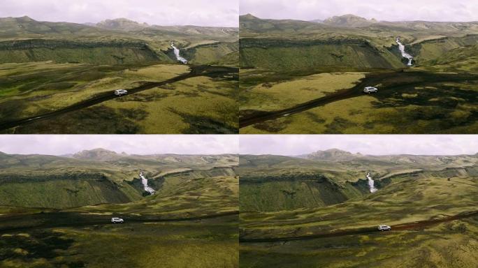 背景为瀑布的4x4 SUV汽车在山路上行驶的空中拍摄