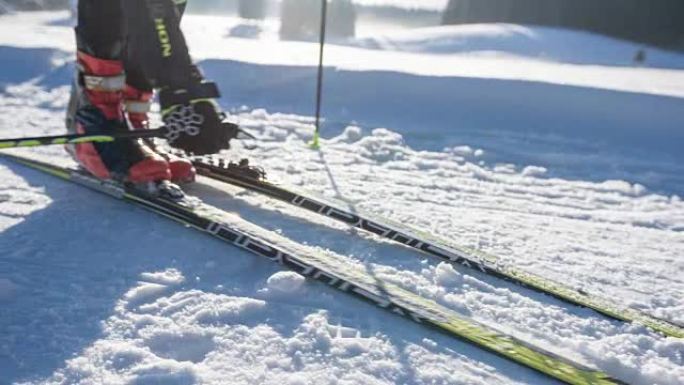 越野滑雪者走到滑雪板上，将它们绑起来